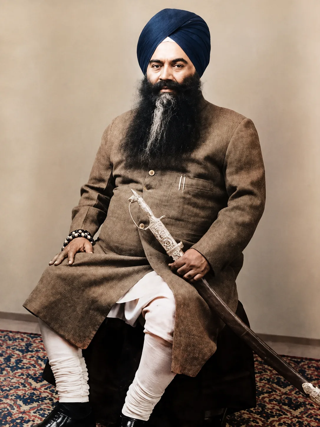Seated formal portrait of Jathedar Santokh Singh in a navy turban, holding a kirpan.