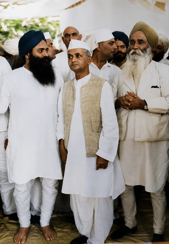 Standing among political figures at an outdoor gathering under a canopy.