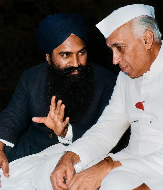 Seated in conversation with Prime Minister Jawaharlal Nehru, who is gesturing mid-sentence.